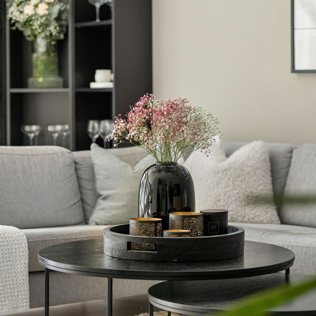 Elegant black vase with pink flowers on stylish dark coffee table