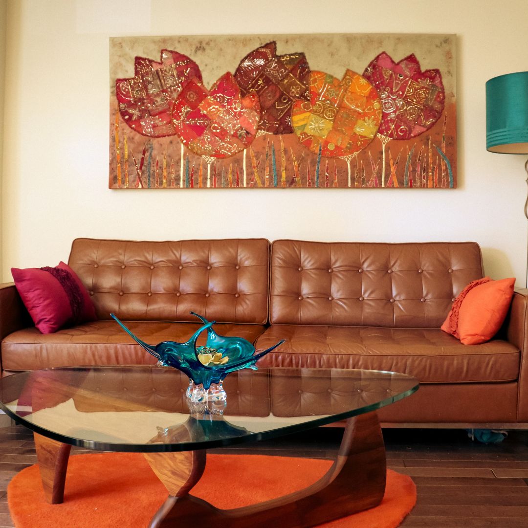 Colorful floral canvas wall art above tufted brown leather sofa